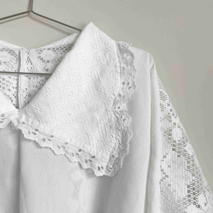 a white blouse hanging on a clothes rack.