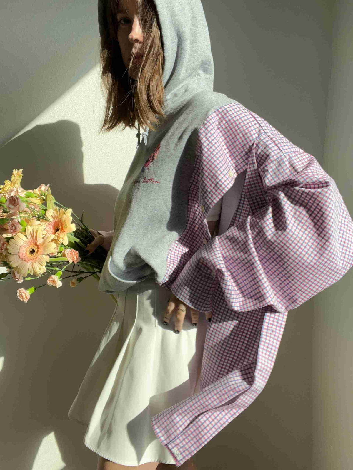 a woman in a hoodie holding a bouquet of flowers.