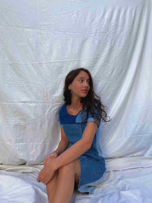 a woman sitting on a white sheet with her legs crossed.