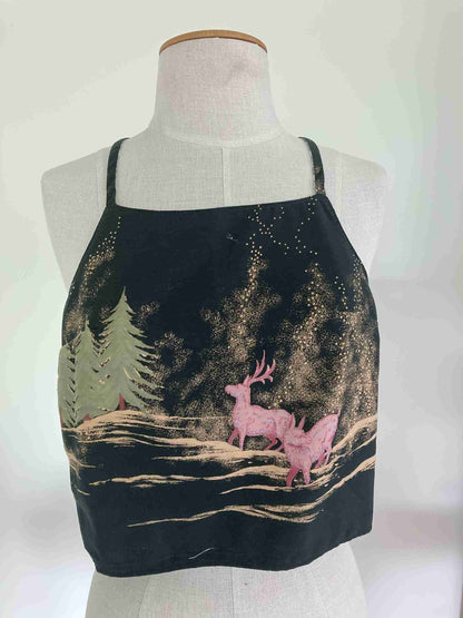 a black apron with a pink deer and pine trees on it.