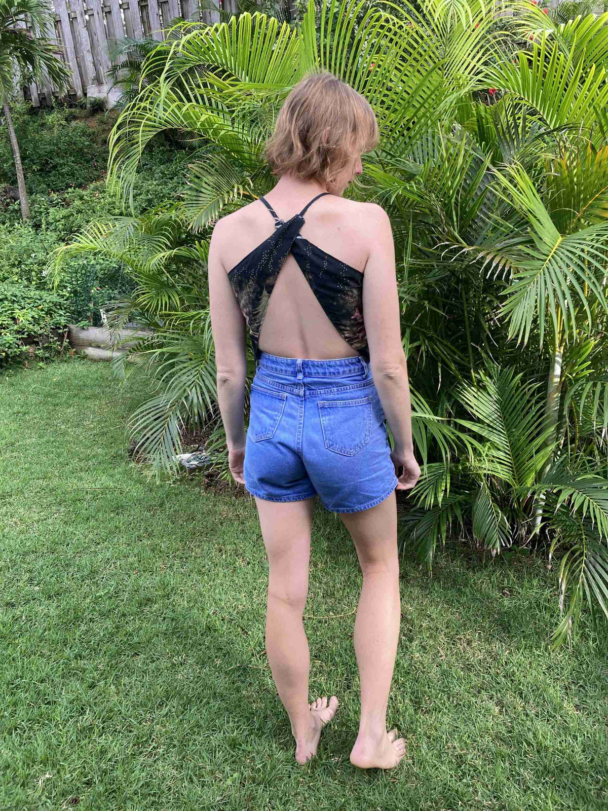 a woman standing in the grass with her back to the camera.