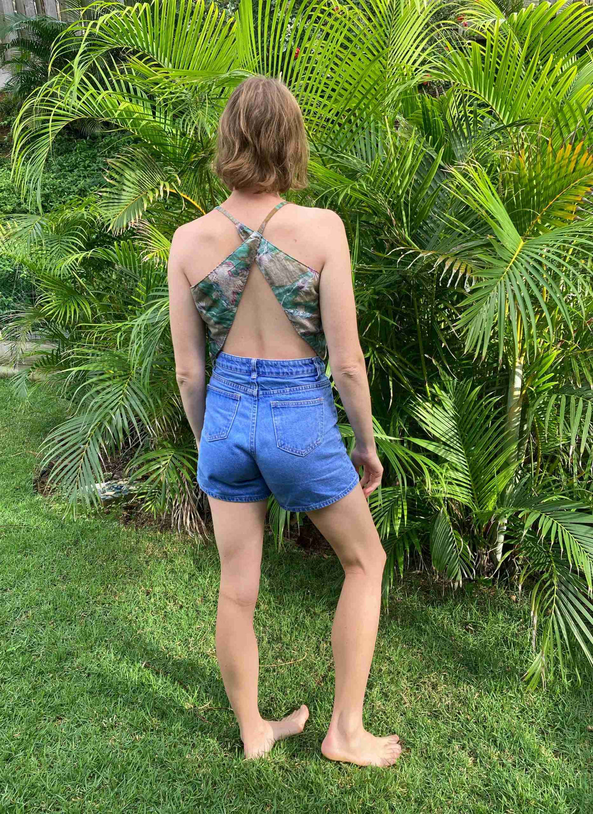 a woman standing in the grass with her back to the camera.