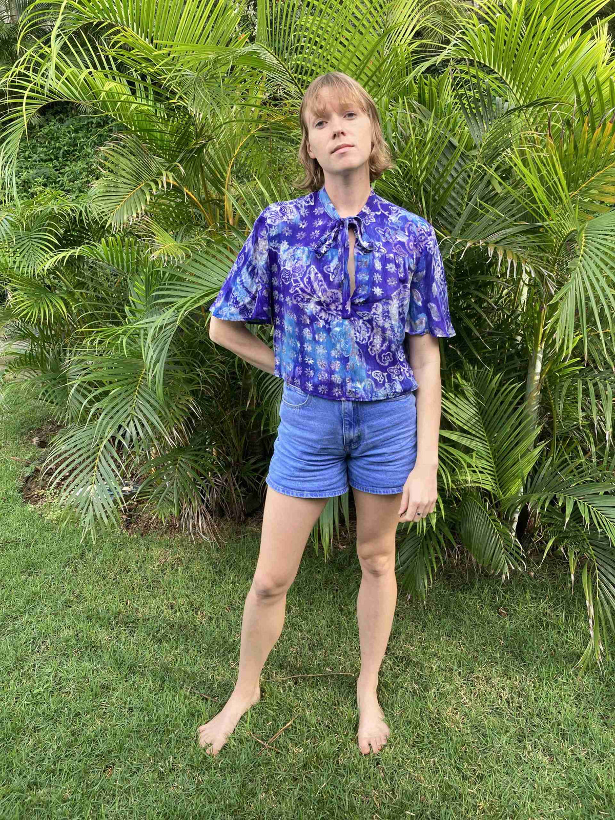 a woman standing in front of a bush.