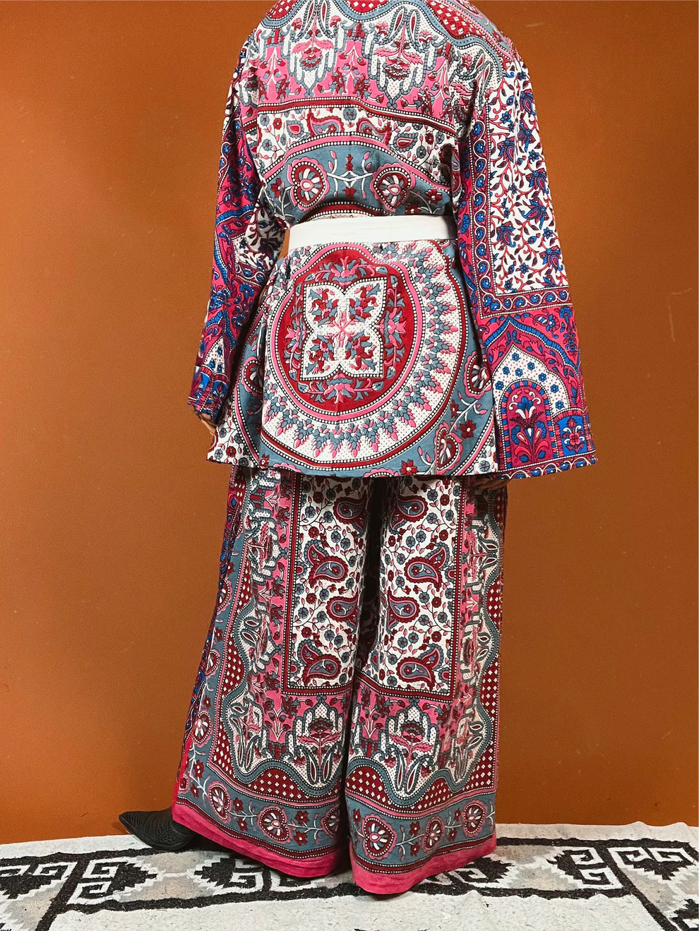 a woman in a colorful outfit standing in front of a wall.