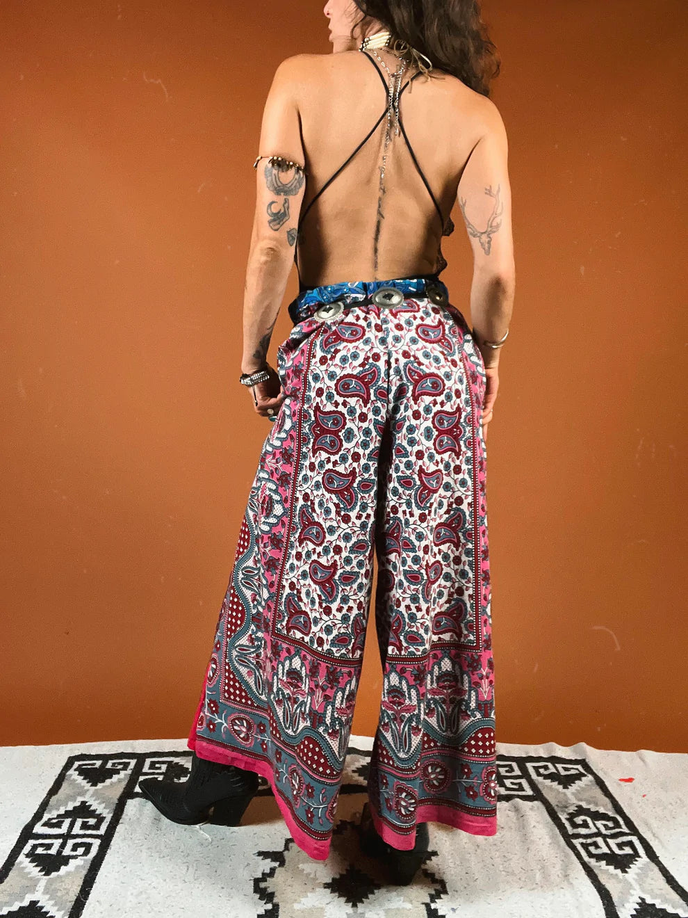 a woman with tattoos on her back standing on a rug.