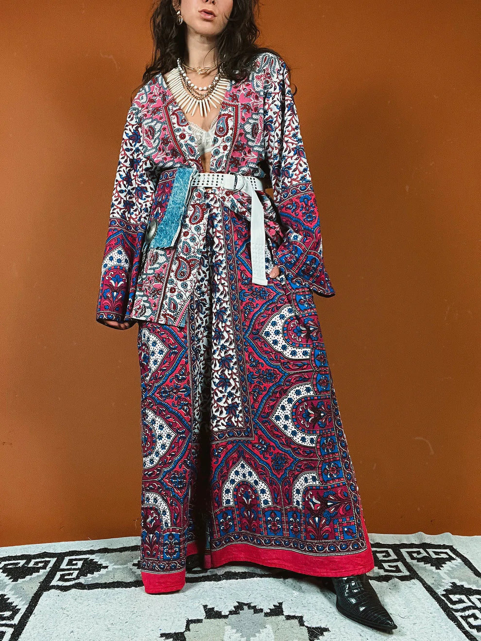a woman in a long dress standing on a rug.