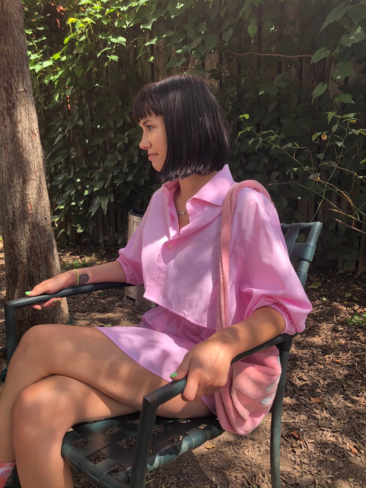 A woman in the Pretty In Pink 2 piece shirt skirt set sitting on a bench.