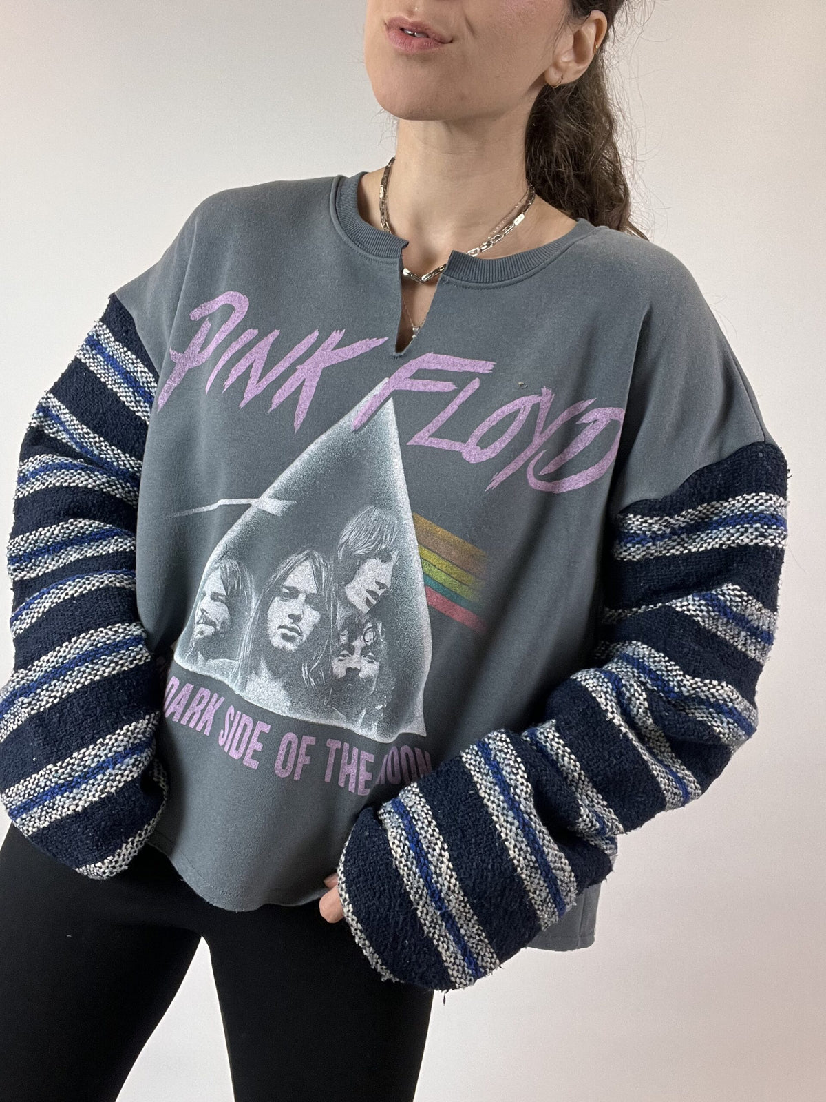 a woman wearing a pink floyd sweatshirt and black leggings.