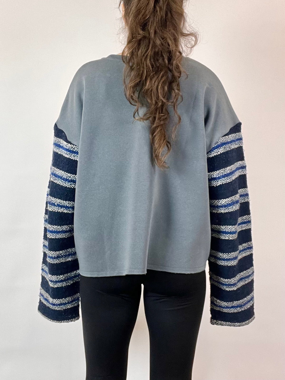 the back of a woman's jacket with a striped sleeve.