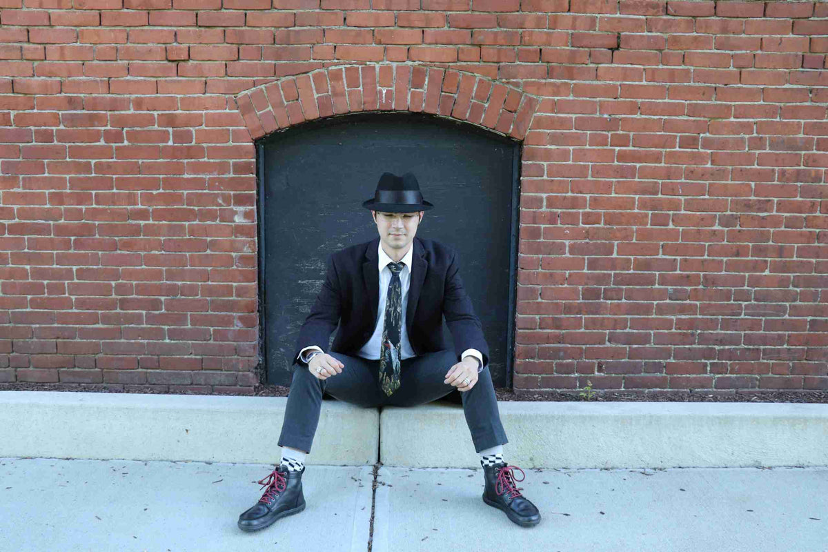 a man in a suit and tie sitting on a sidewalk.