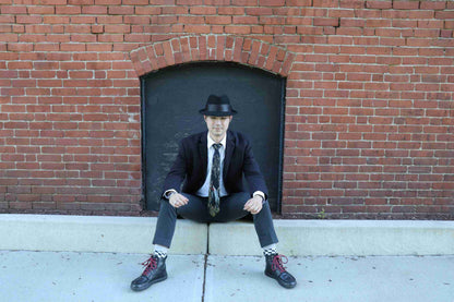 a man in a suit and tie sitting on a sidewalk.