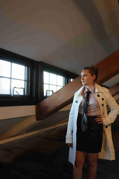 a woman in a white trench coat and tie.