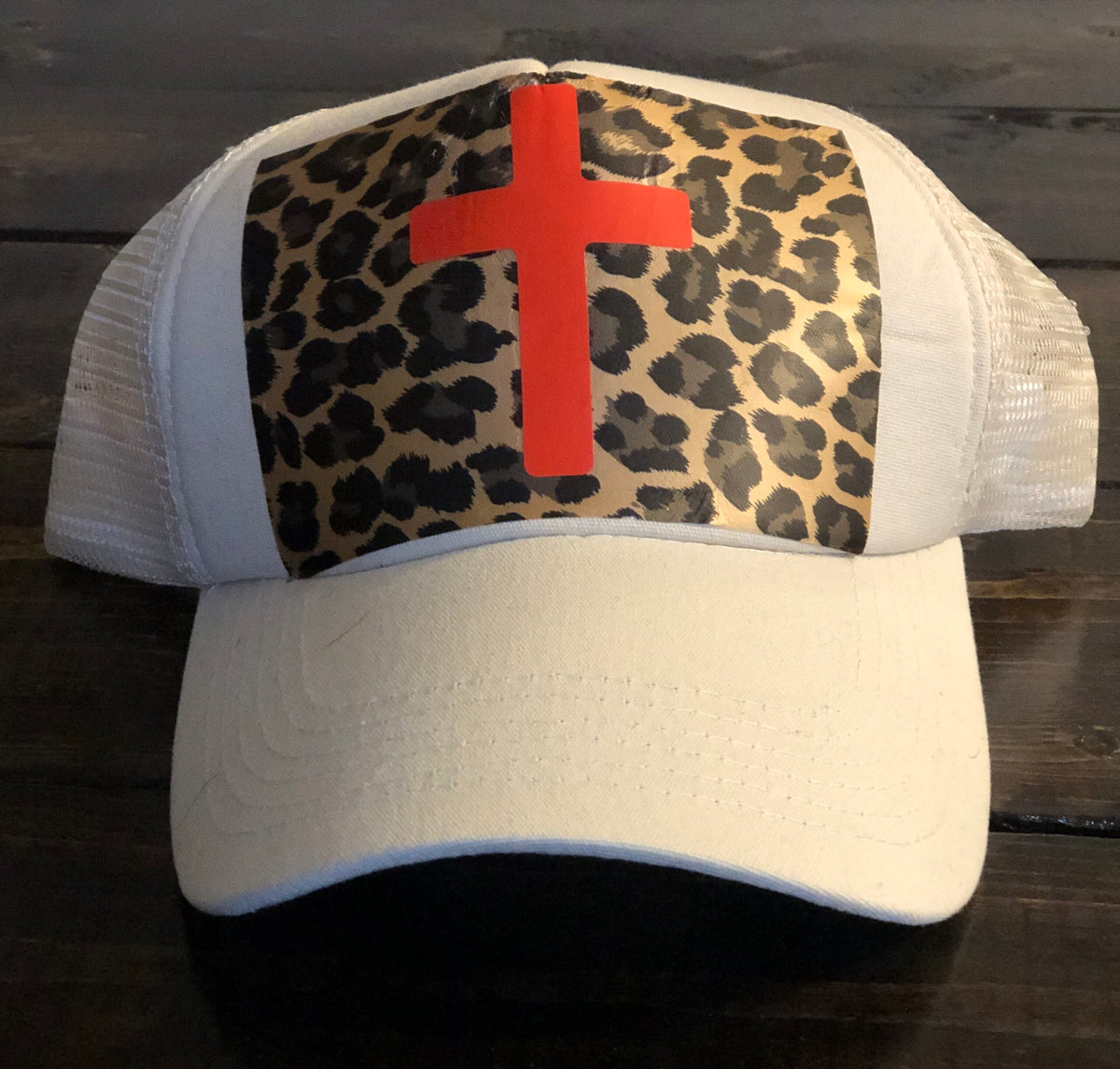 A white hat with a leopard print and a cross on it.