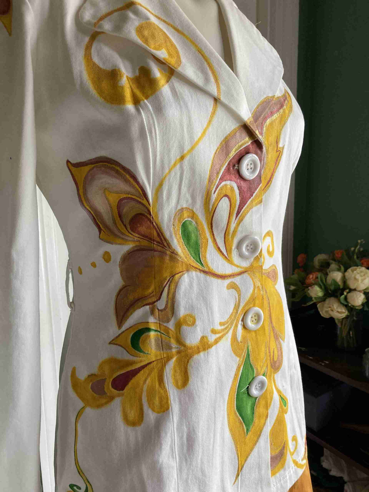 a white dress with yellow and green designs on it.