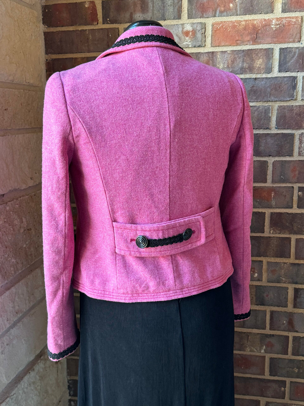 A mannequin wearing a pink jacket with black trim.