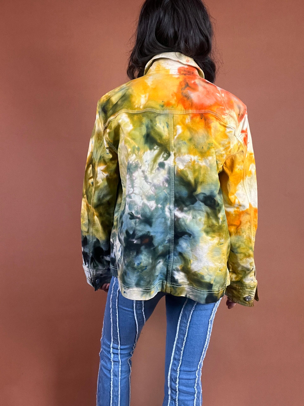 The back of a woman wearing a tie dye jacket.