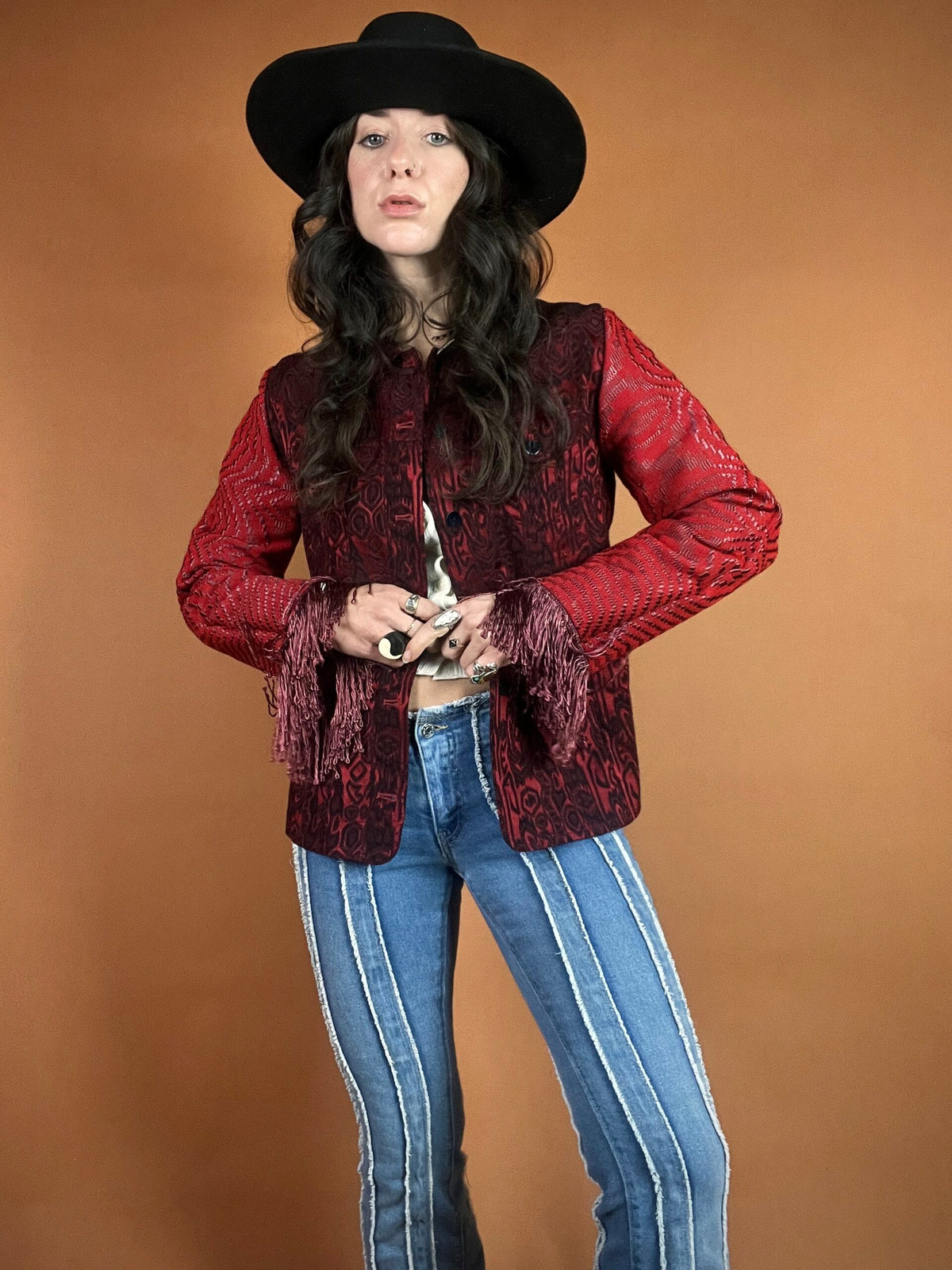 A woman in a cowboy hat and jeans holding a gun.