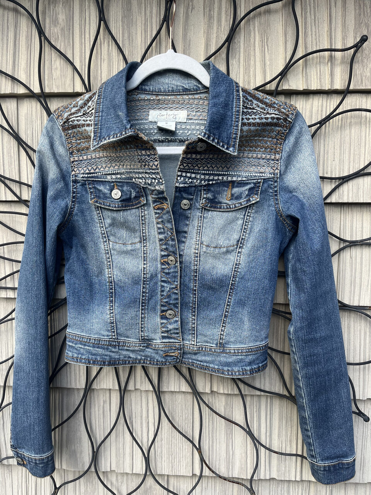 A denim jacket hanging on a wall.