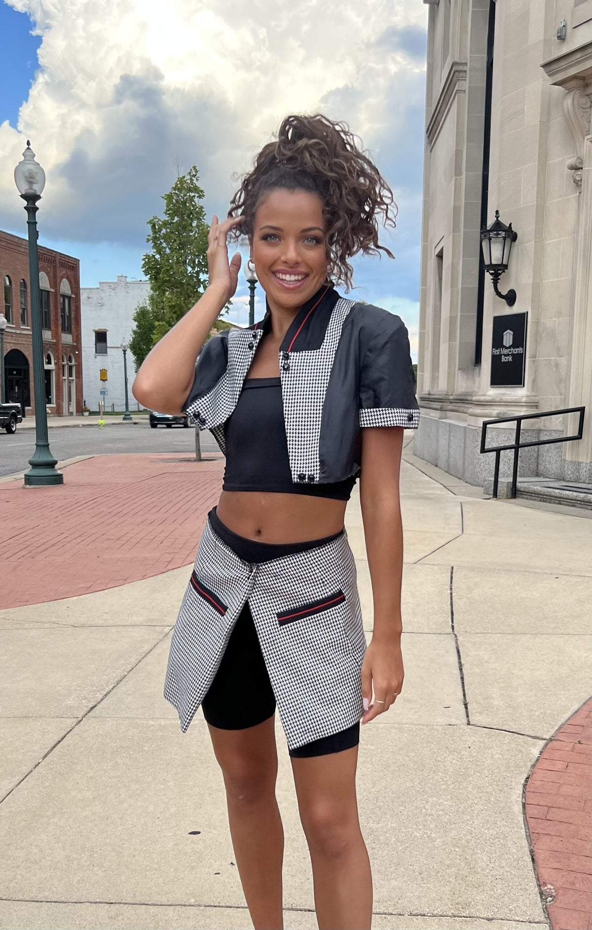 A young woman wearing a grey and black crop top and shorts.