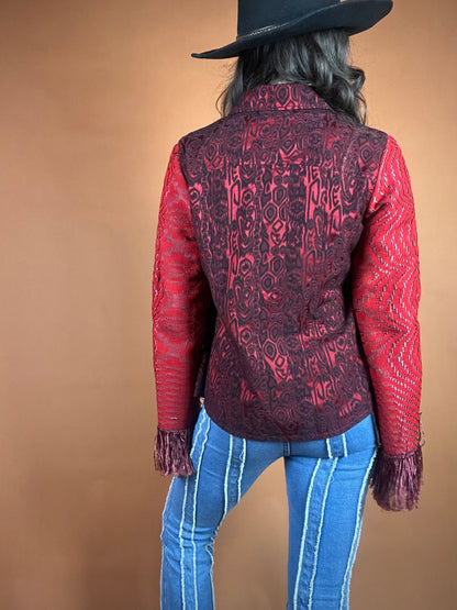 The back view of a woman wearing a red jacket and jeans.
