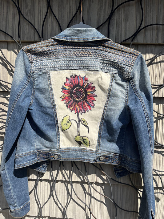 A denim jacket with a sunflower on it.