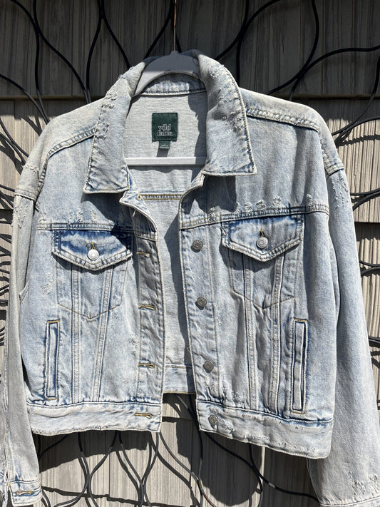 A light blue denim jacket hanging on a fence.