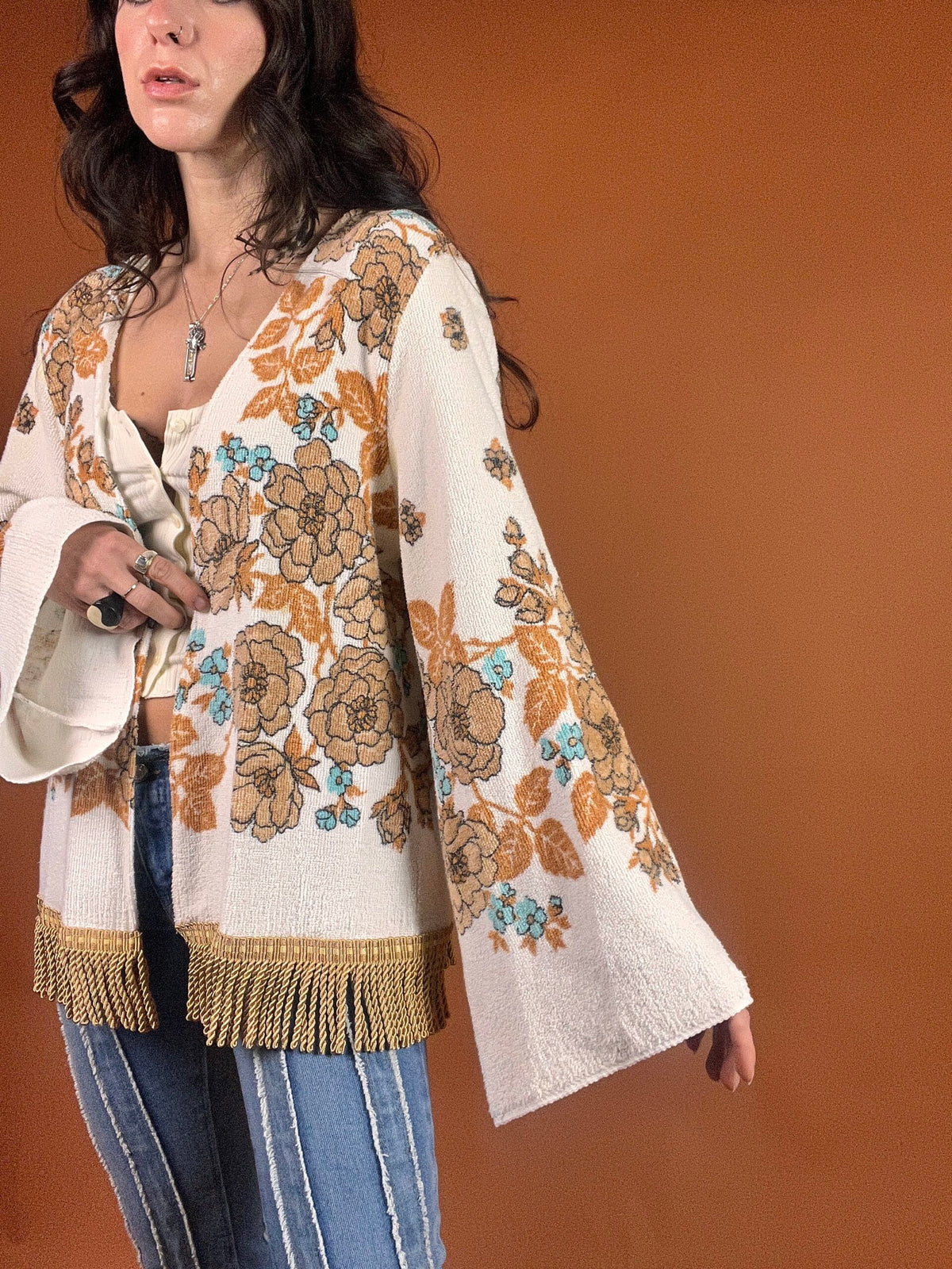 A woman wearing a fringed jacket and jeans.