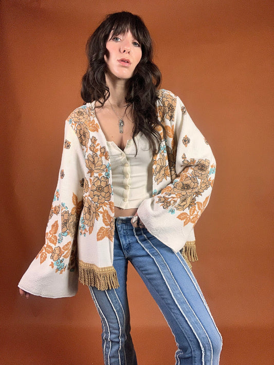 A woman wearing a fringed jacket and jeans.