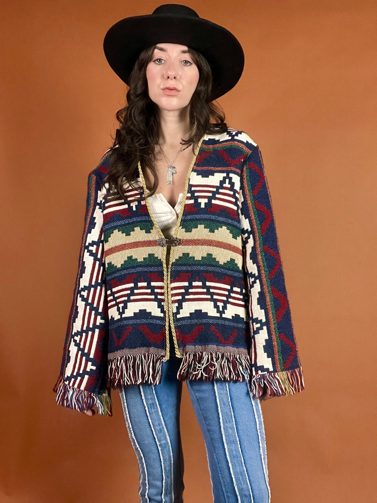 A woman in a hat and jeans poses for a photo.