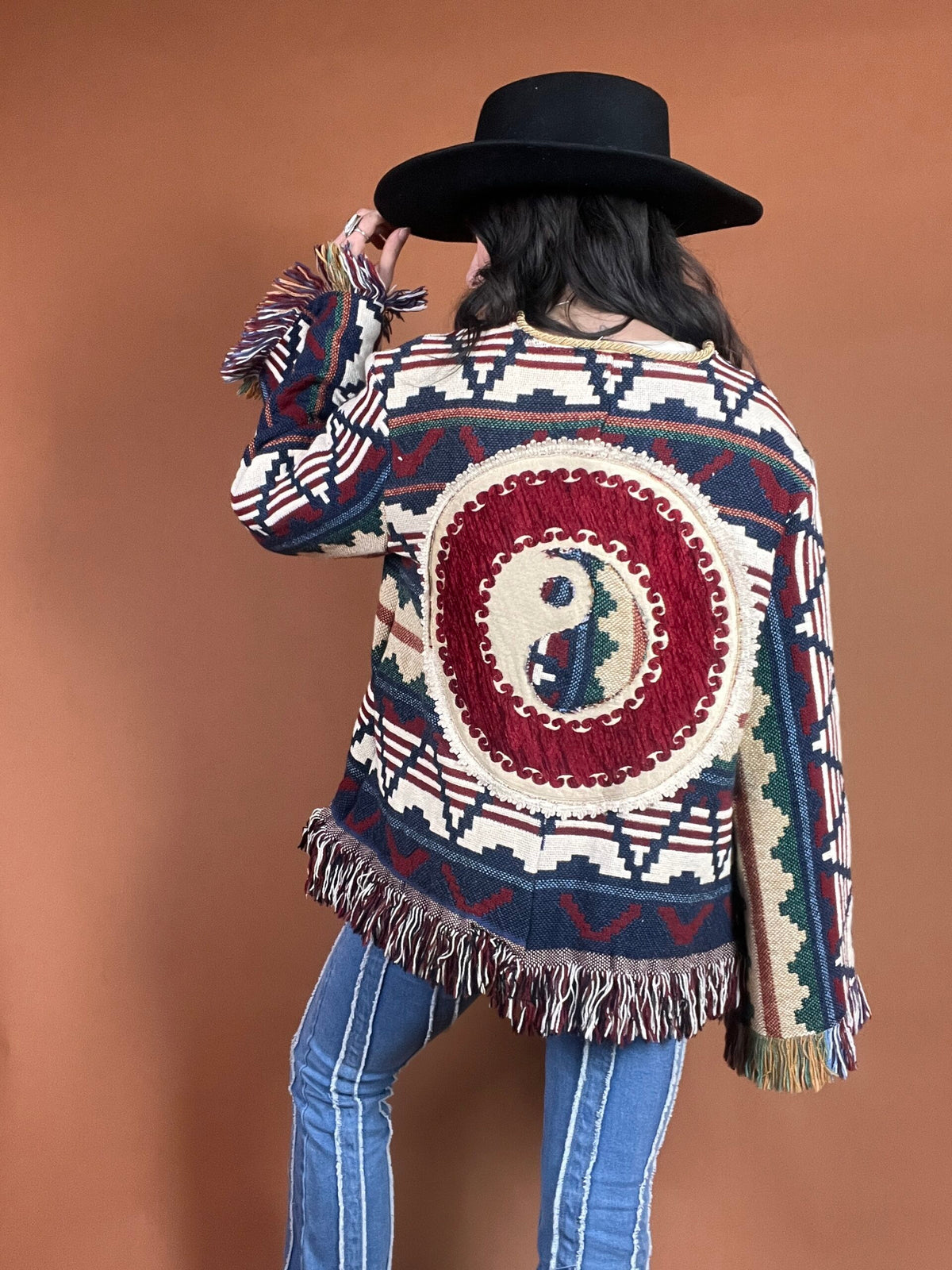 A woman wearing a fringed jacket and jeans.