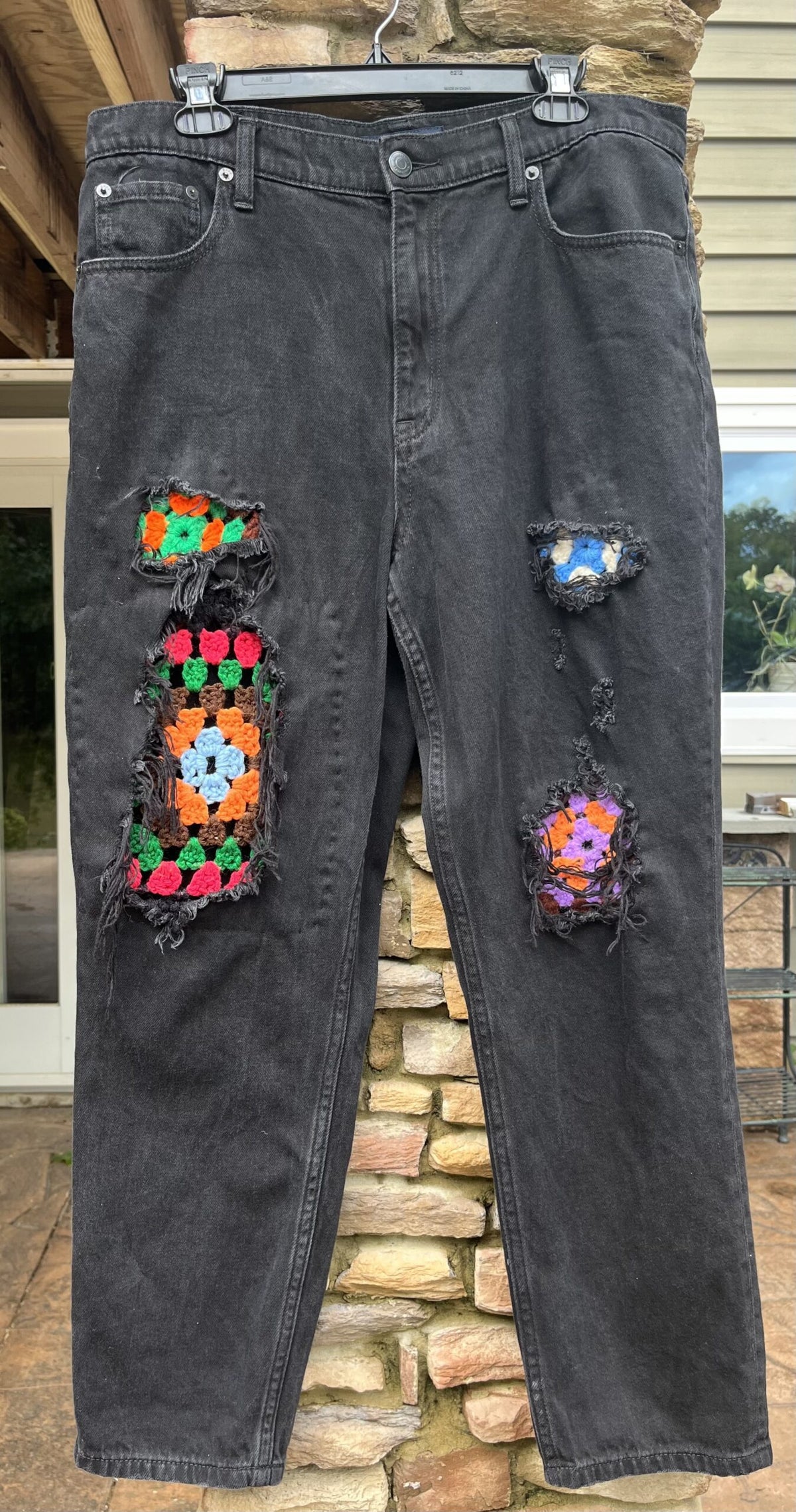 A pair of black jeans with colorful patches on them.