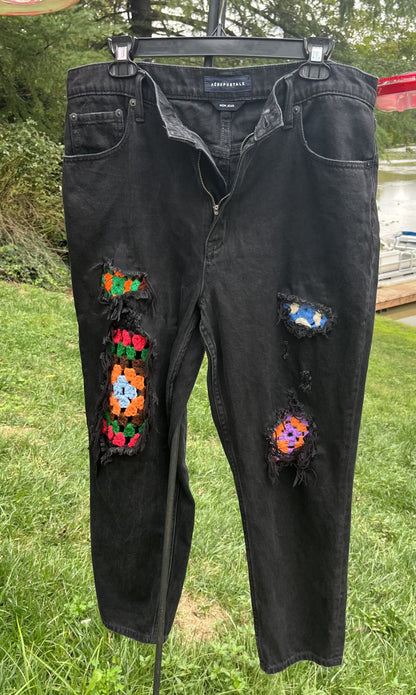 A pair of black jeans with colorful patches on them.