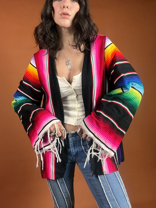 A woman wearing a colorful mexican jacket.