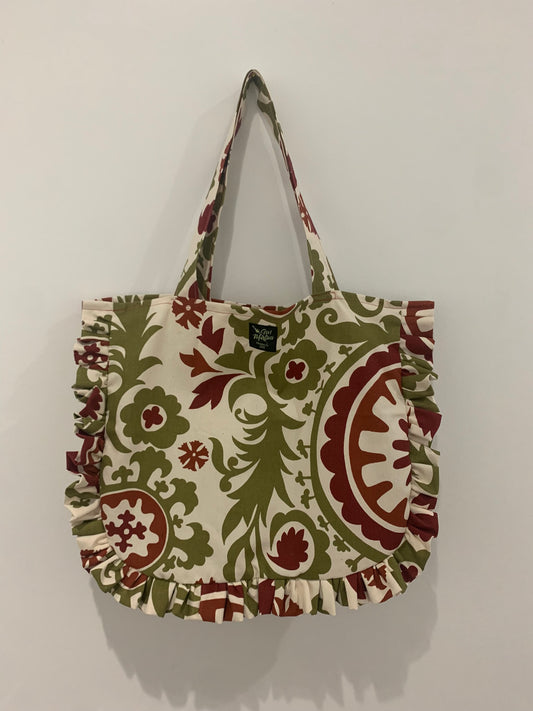 a green and red ruffled tote bag hanging on a wall.
