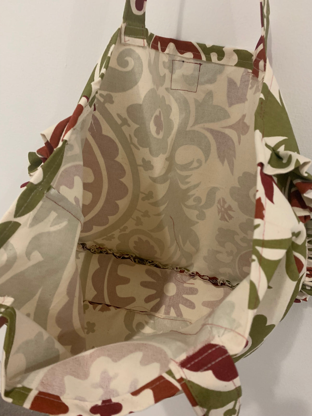 a green and brown tote bag hanging on a wall.