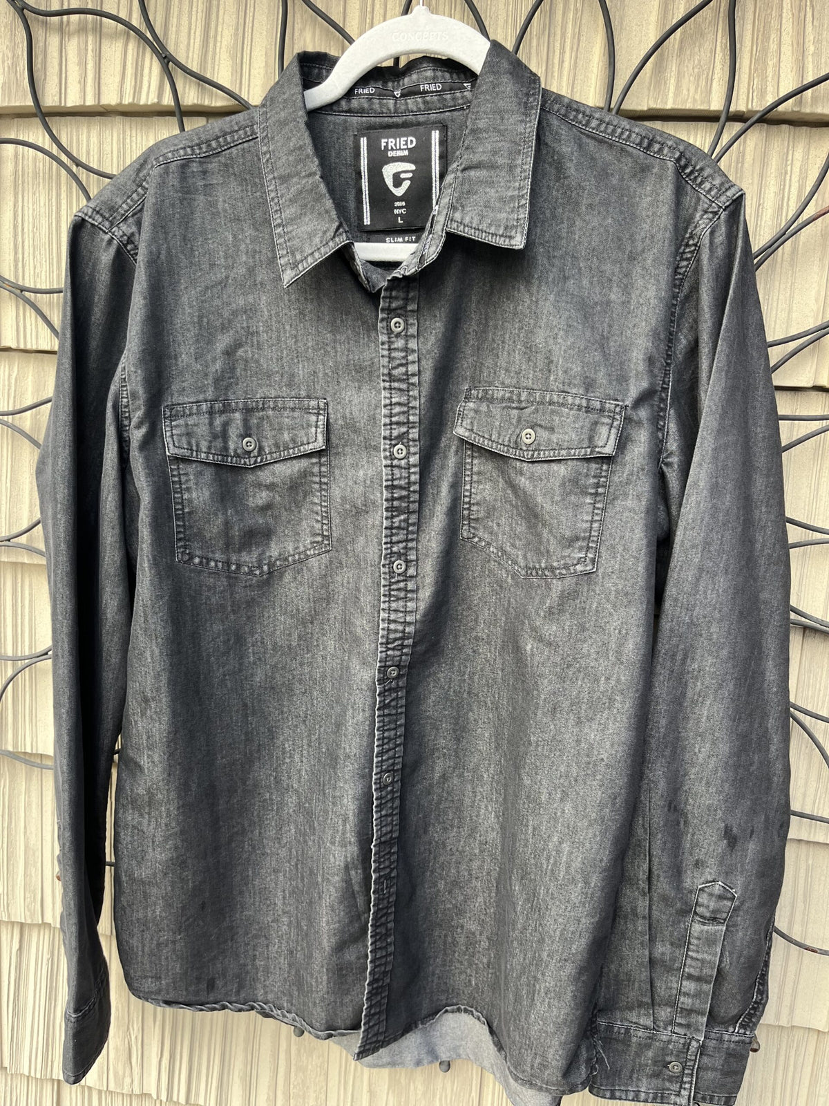 A grey button down shirt hanging on a wall.