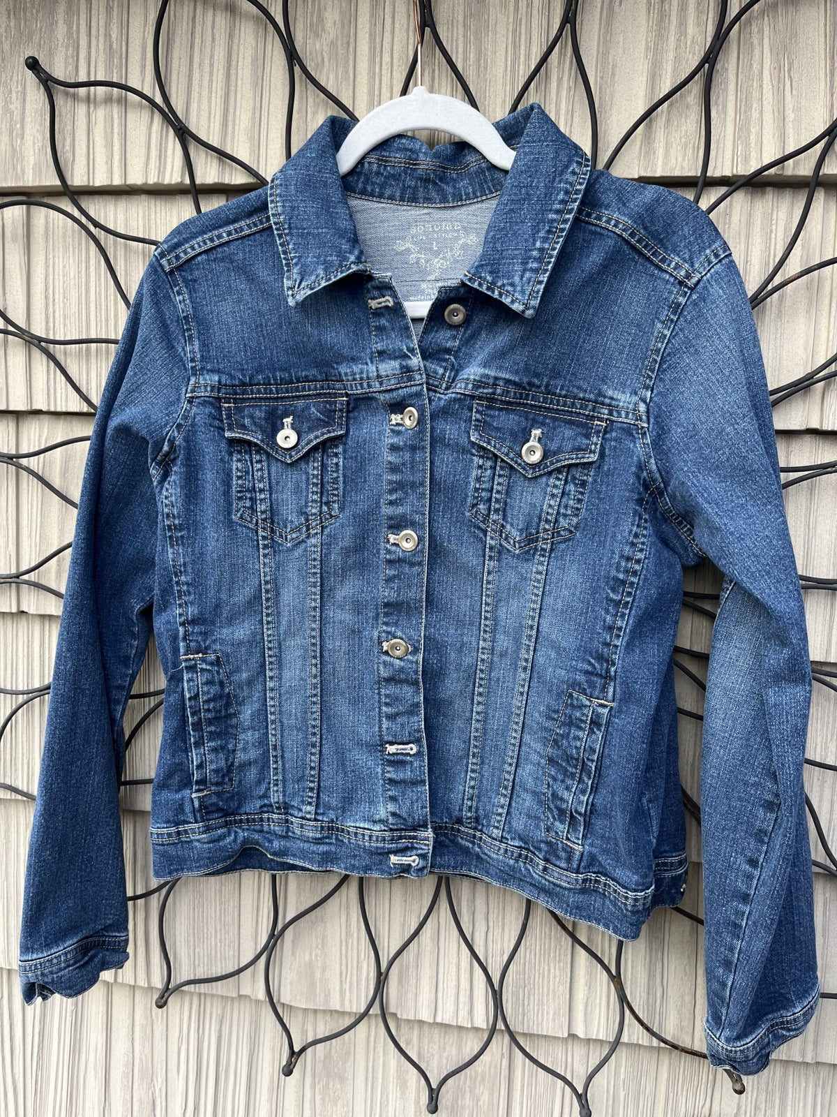 A denim jacket hanging on a wall.