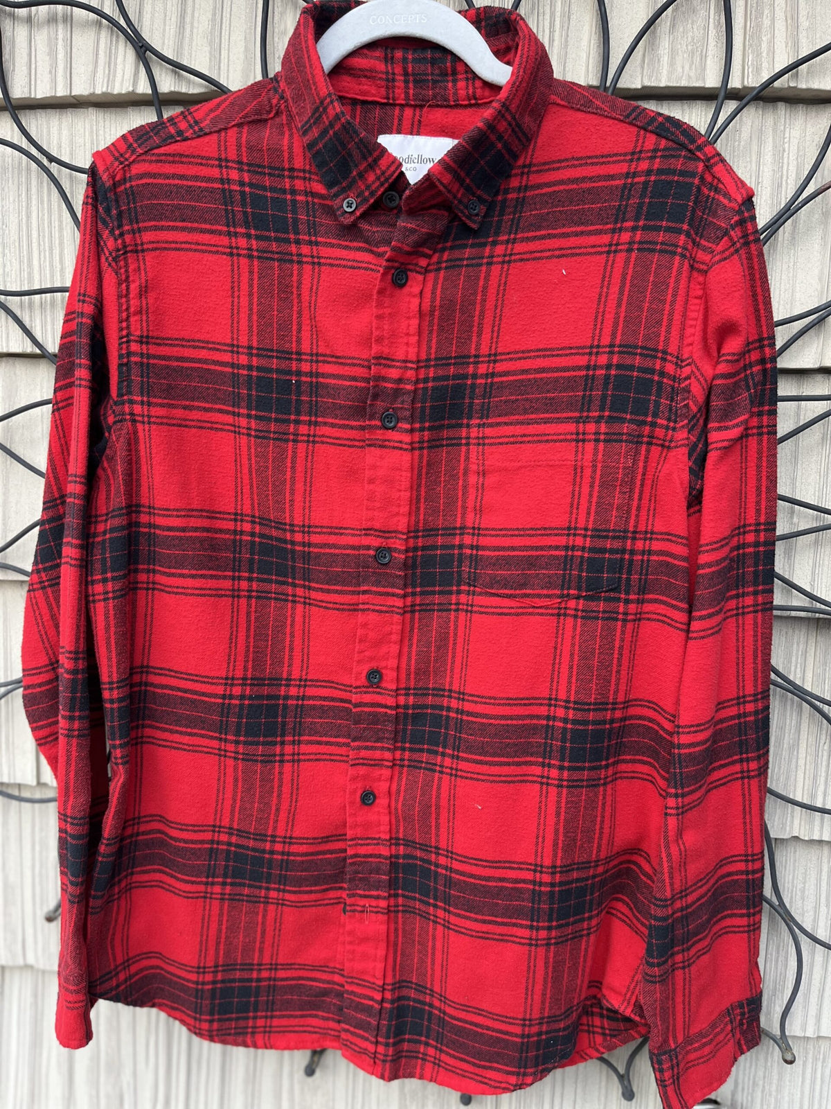 A red and black plaid shirt hanging on a wall.