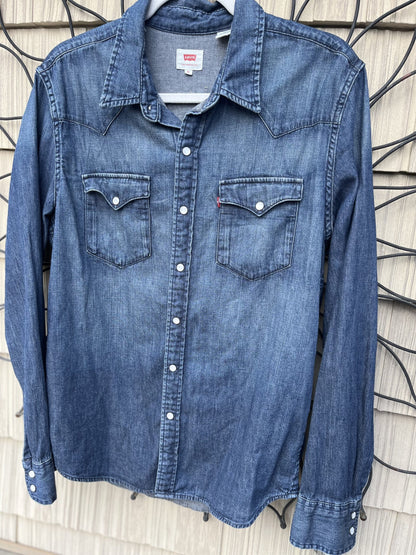 A blue denim shirt hanging on a wall.
