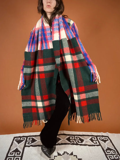 a woman standing on a rug wearing a plaid blanket.