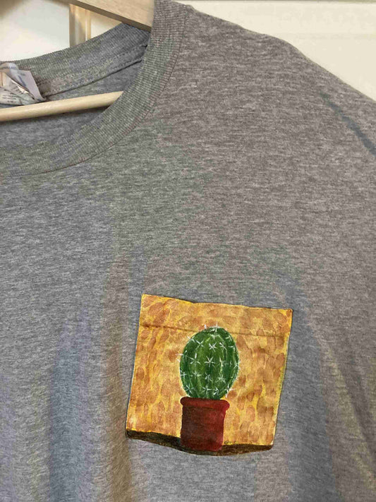 a t - shirt with a picture of a cactus in a pot on it.