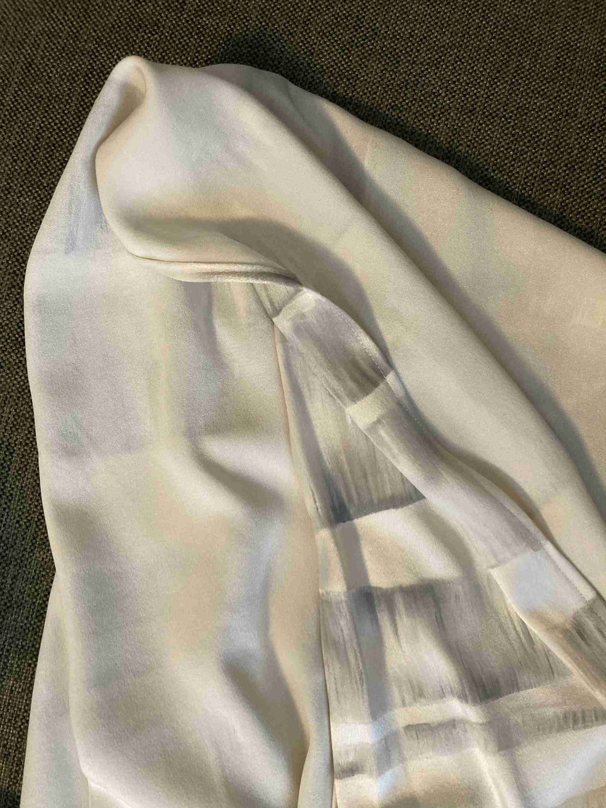 a white shirt laying on top of a brown couch.