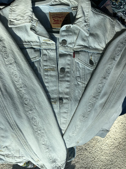 A levi's denim jacket is laying on the ground.