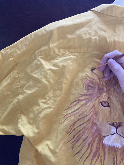 a person drawing a lion on a yellow shirt.