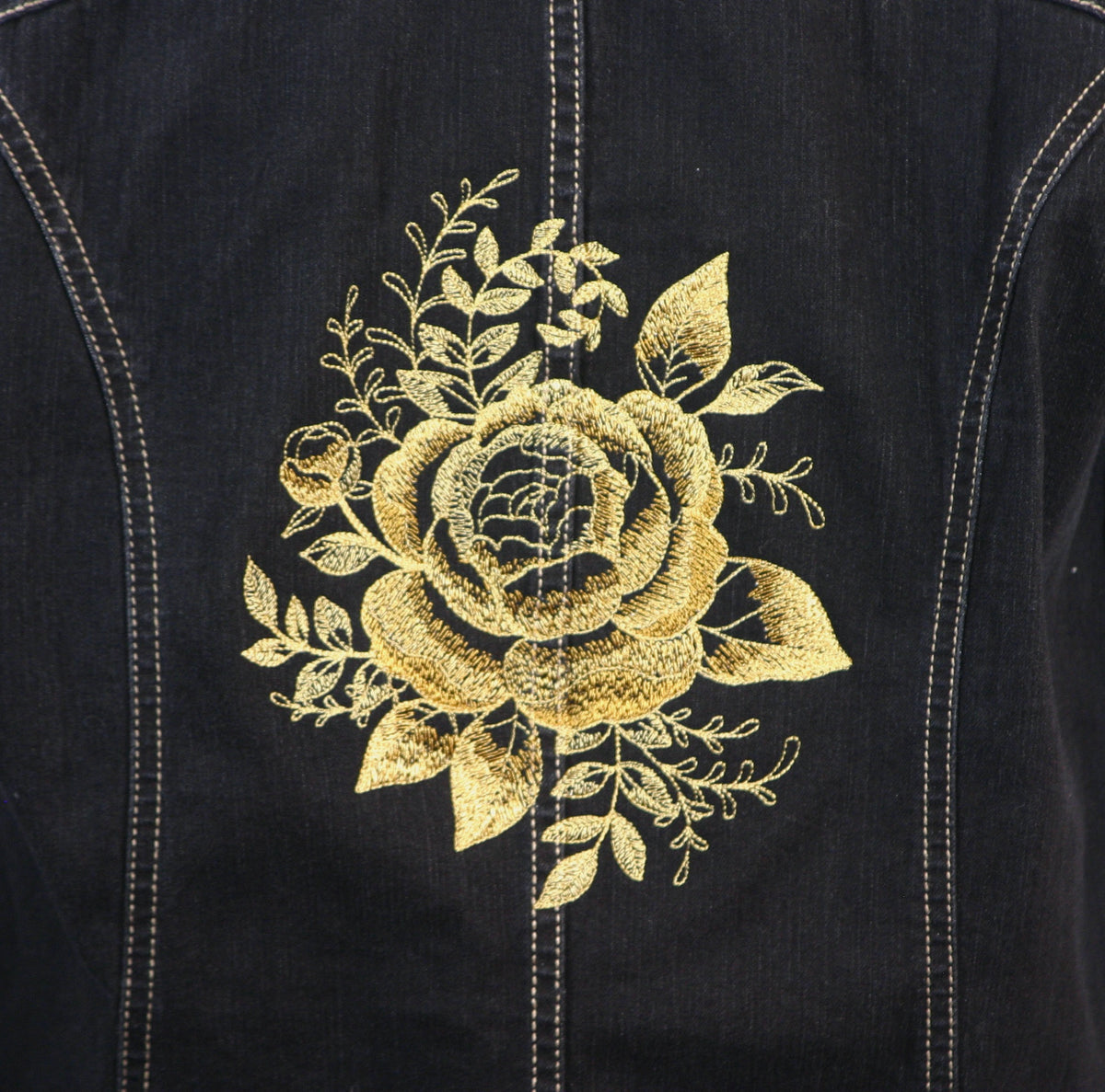 The back of a denim jacket with a gold rose embroidered on it.