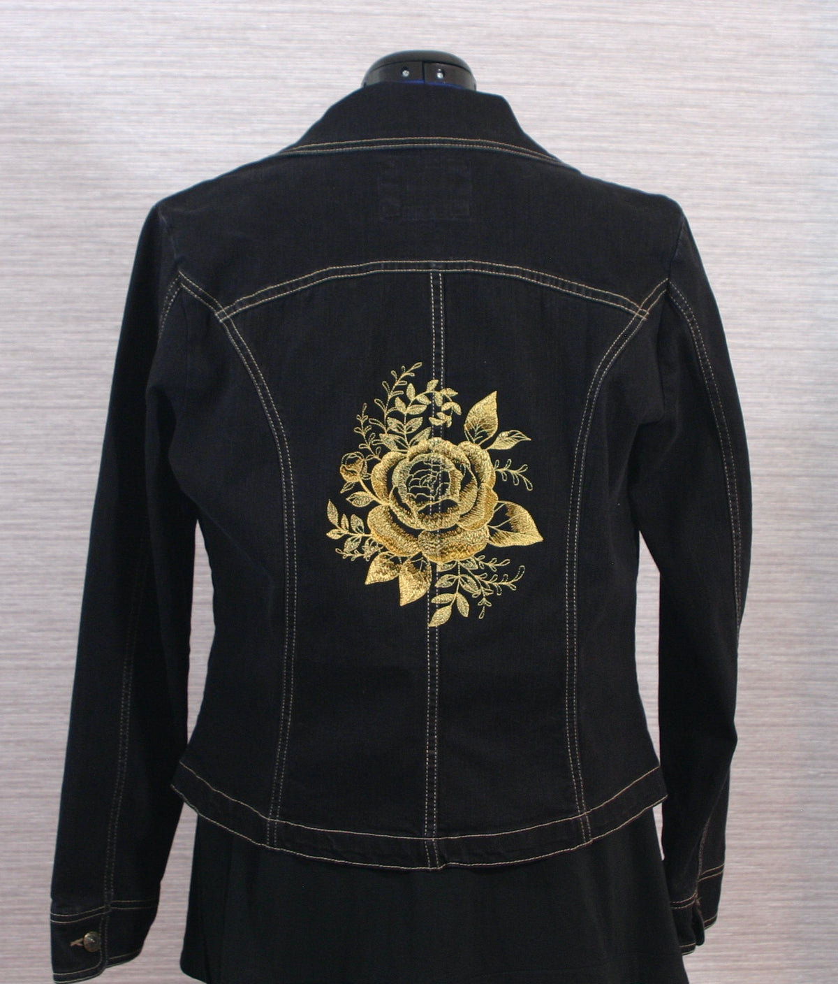 A black denim jacket with gold roses on the back.