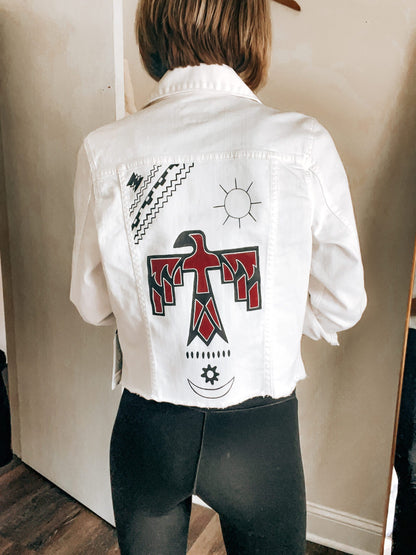 The back of a woman wearing a denim jacket with an eagle on it.