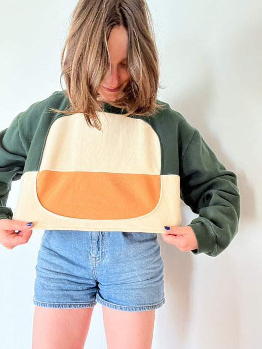 a woman holding a piece of paper with a Sweatshirt of the Year Block Cropped Sweatshirt on it.
