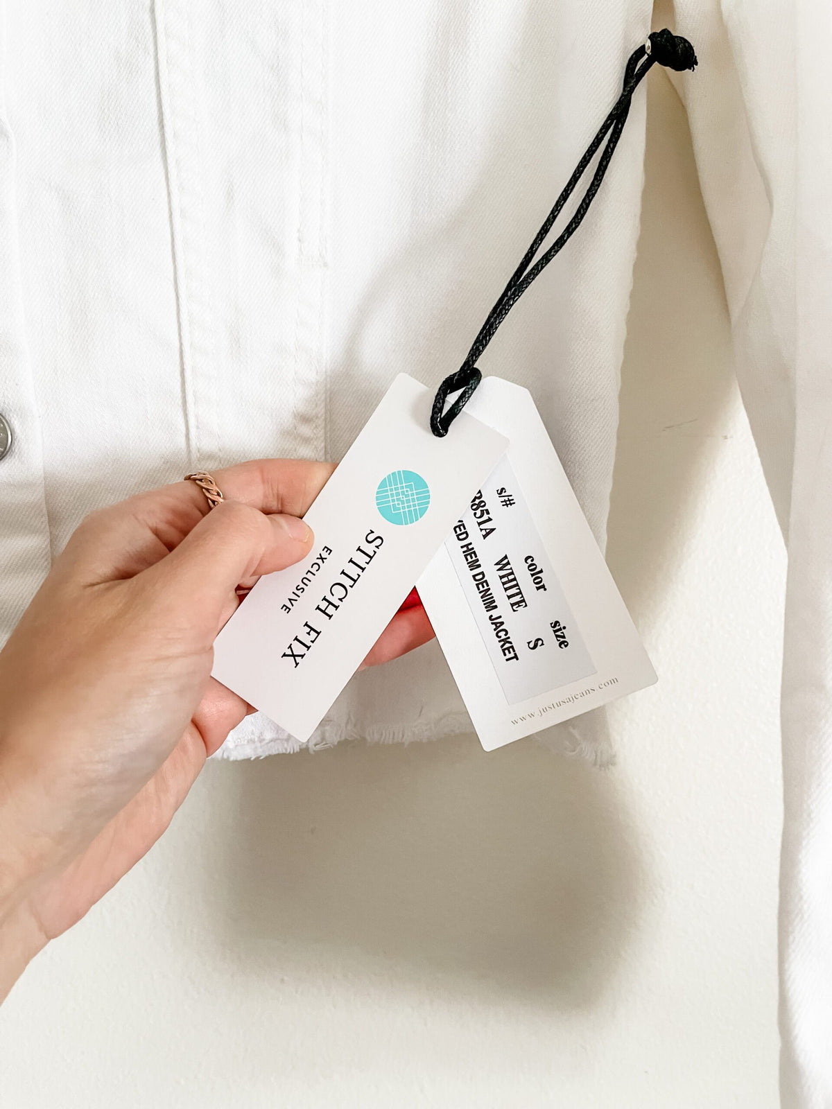 A person holding a tag on a white shirt.