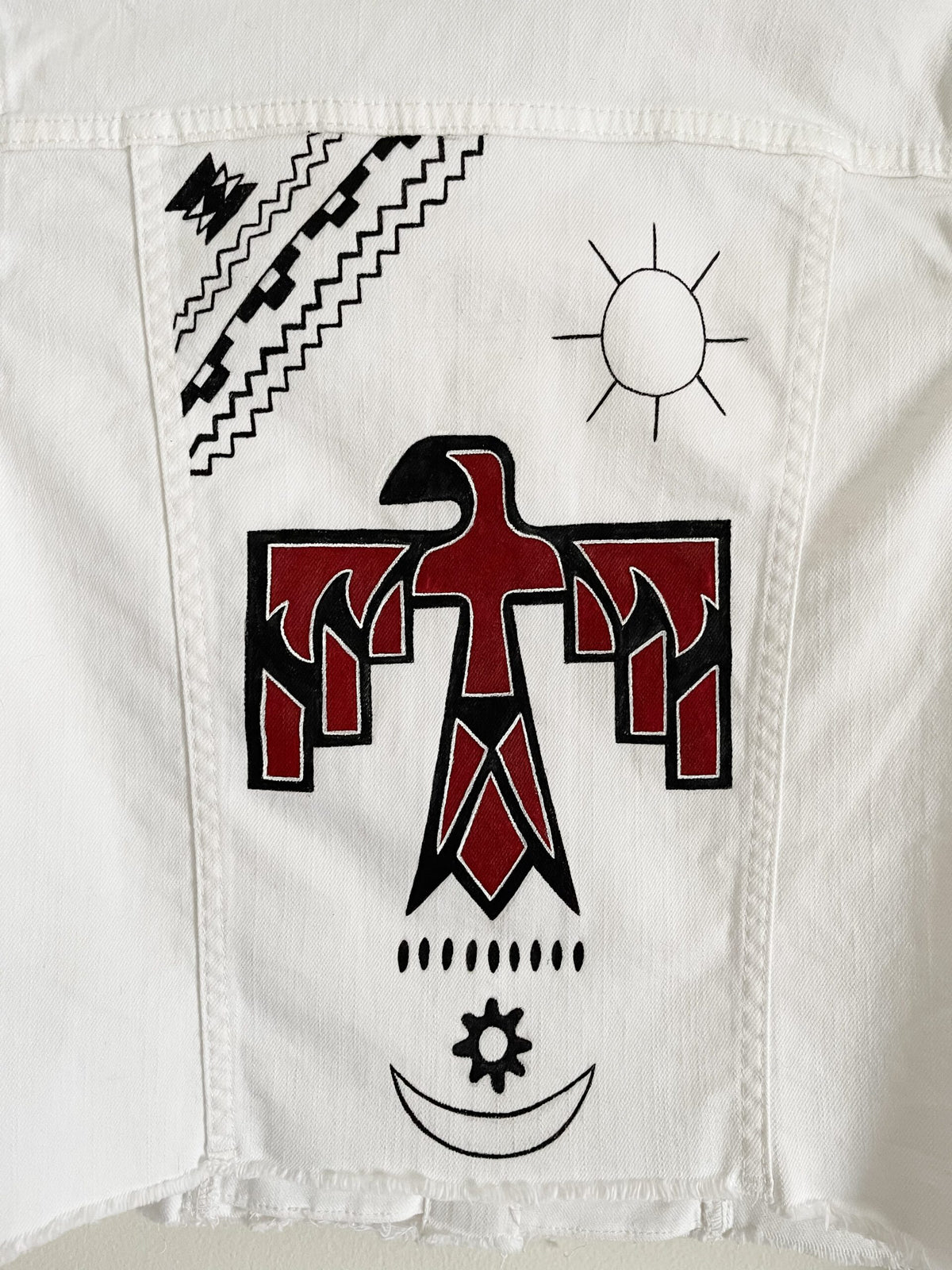 A white denim jacket with a red and black eagle on it.